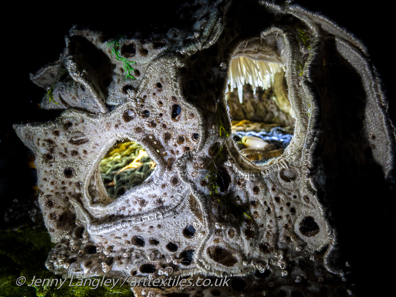 The grotto, lit up by torch light to reveal its textured outer walls and internal stalactities and crystals.