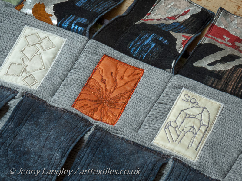Grey flaps representing the slate tiled roof of the grotto have been lifted to reveal samples of the crystals lining its walls.  The underneath of the flaps are brightly coloured and are meant to be a surprise.